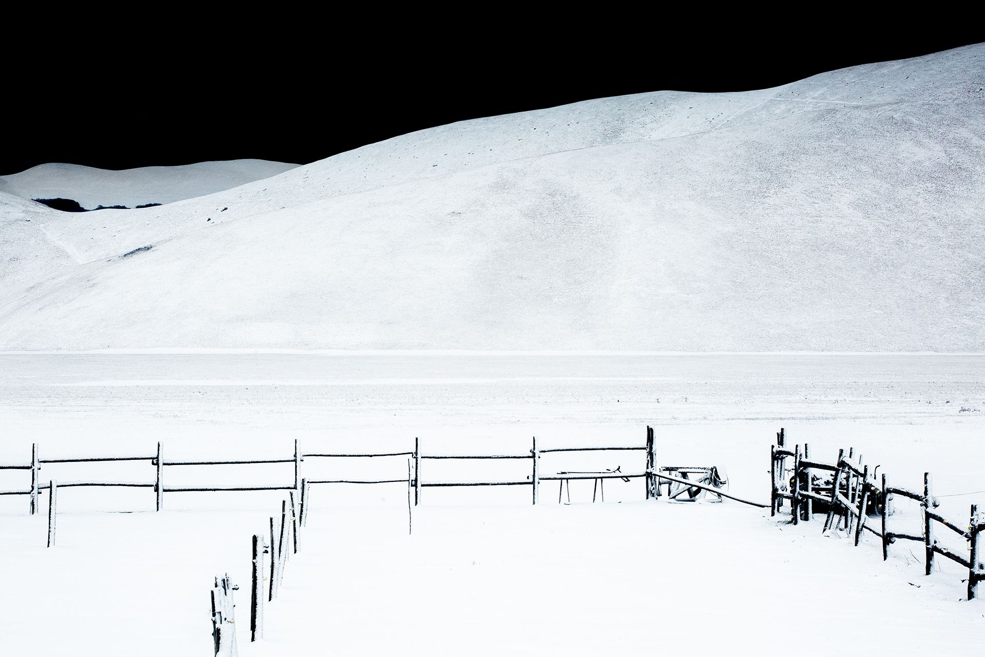 Recinti in legno nella neve ai piedi di una collina bianca