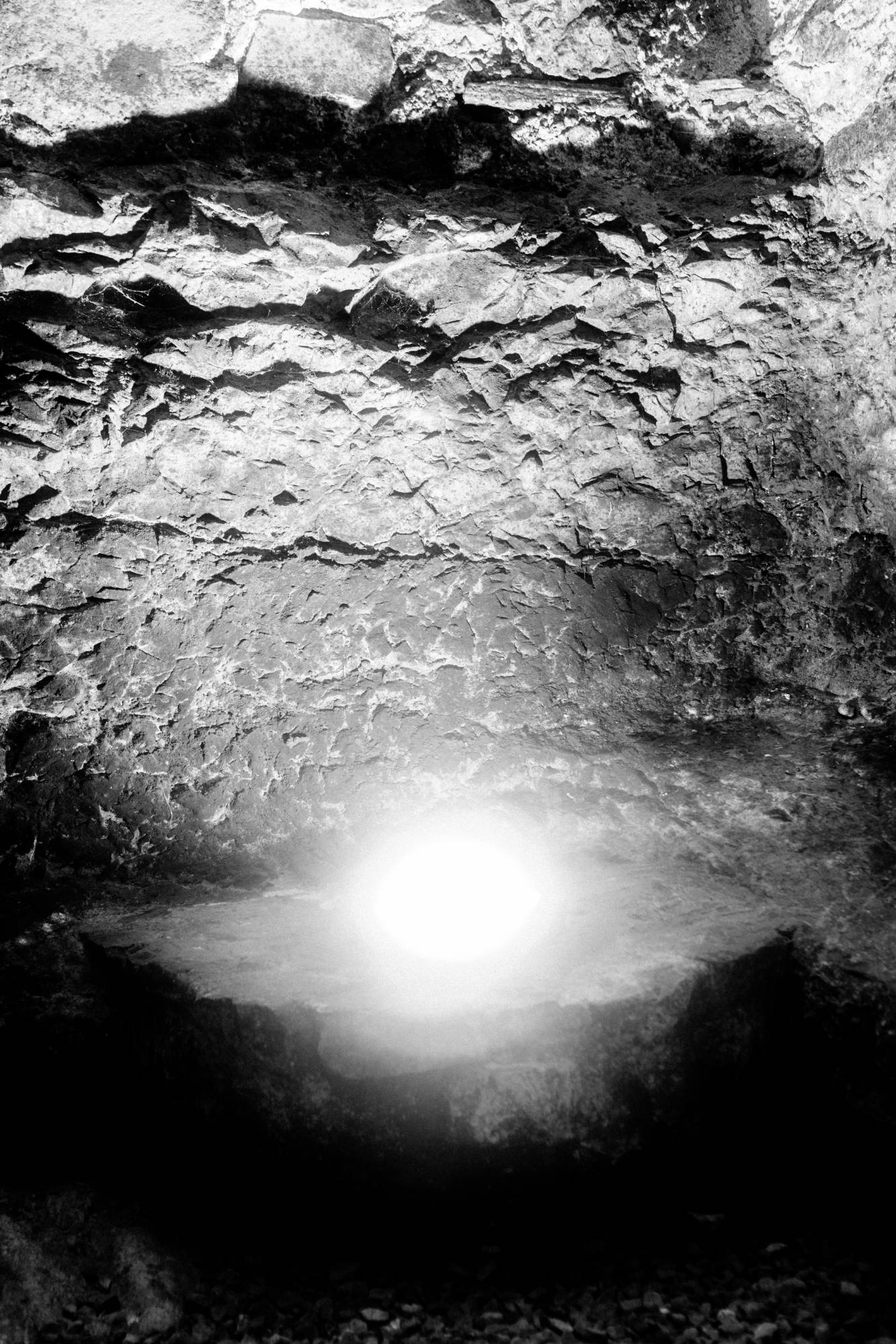 Parete di roccia irregolare con un bagliore di luce in basso