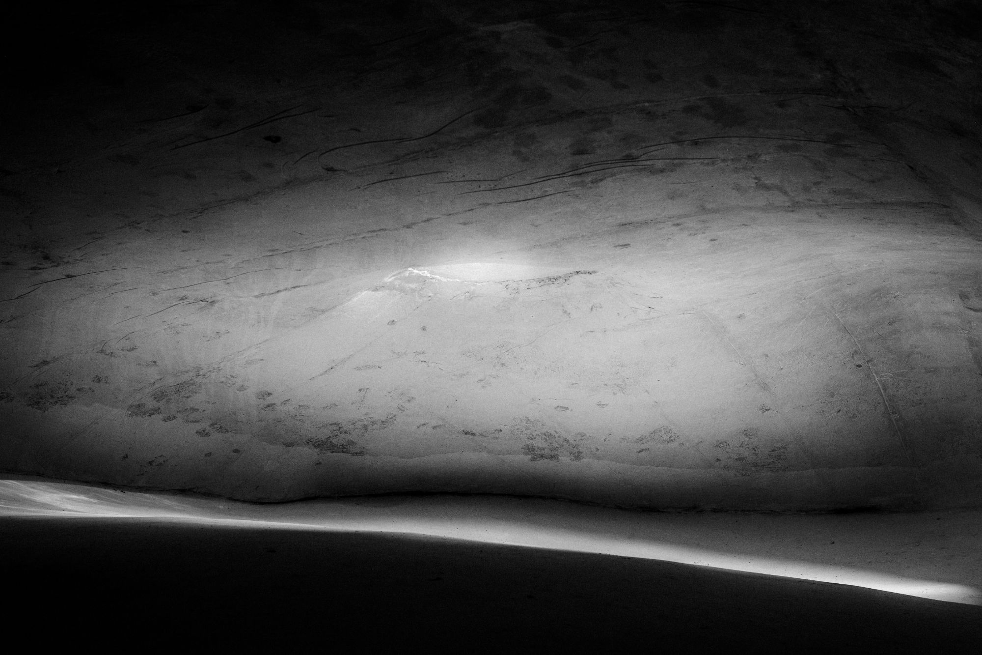 Parete scura e levigata con una fascia di luce sul pavimento