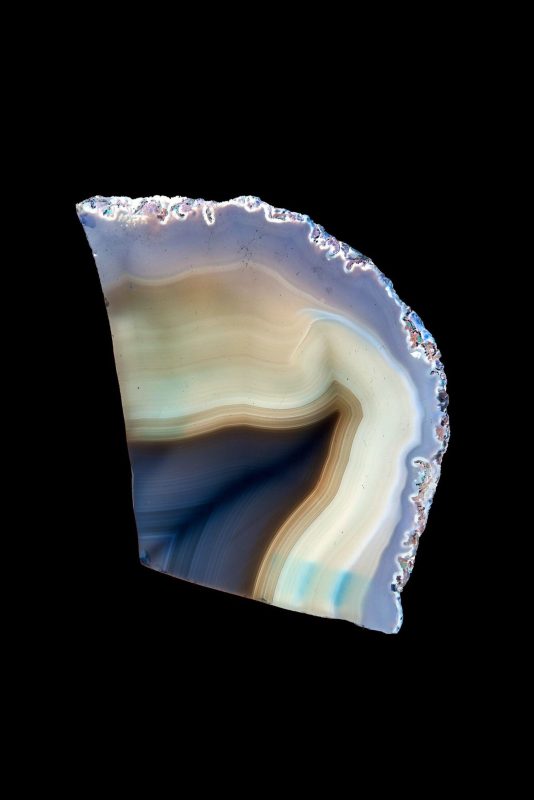 Sezione di agata con venature azzurre e color crema su fondo nero